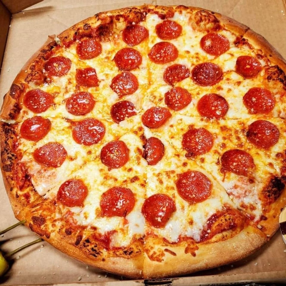 A whole pepperoni pizza with melted cheese and a golden crust, in a cardboard box.