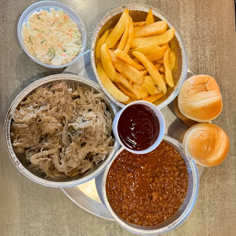 Rebel SmokeHouse and Burgers BBQ meal with pulled pork, fries, baked beans, coleslaw, and buns.