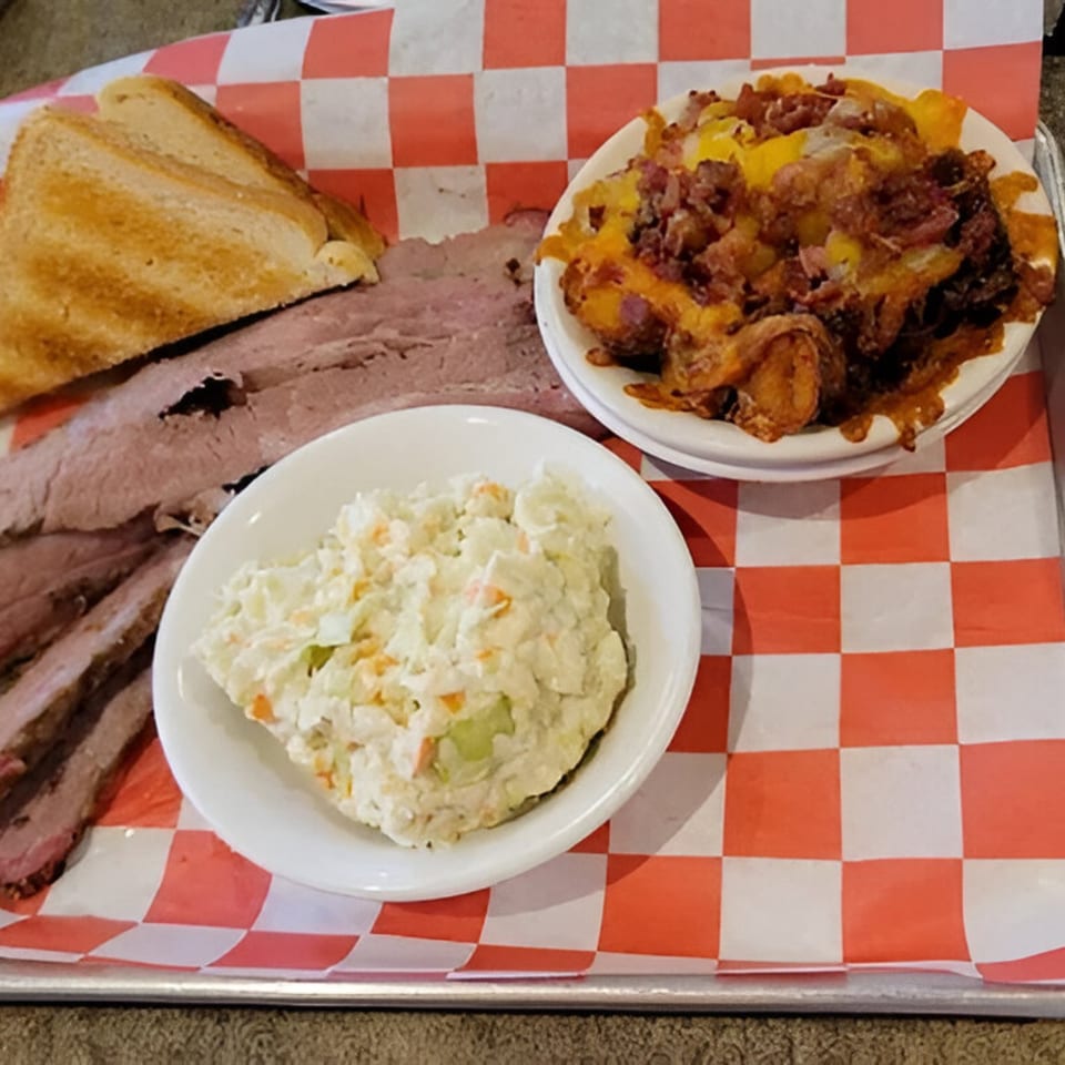 Rebel SmokeHouse and Burgers' brisket platter with coleslaw, cheesy fries, and toasted bread on a checkered tray.